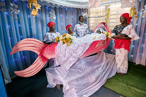 Blue teapot coffin carried by mourners